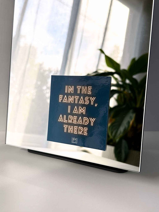 Neon-style mirror manifestation affirmation reading “In the fantasy, I am already there”