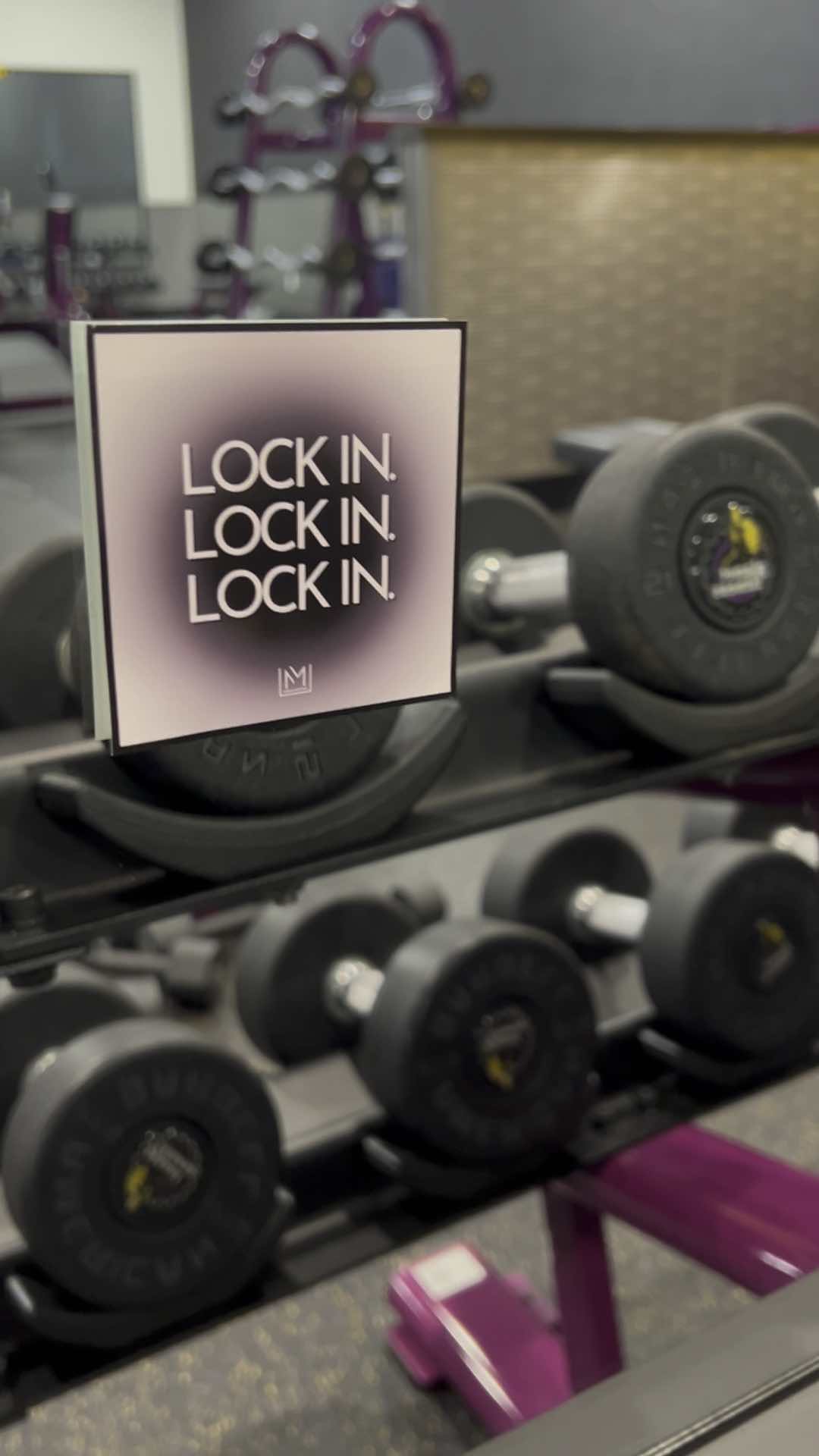 Gym setting with dumbbells and a vinyl mirror affirmation sticker applied to the window displaying 'LOCK IN' text.